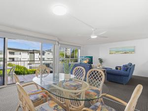 a living room with a glass table and chairs at Surfcomber on the Beach in Maroochydore