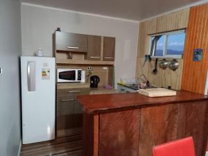 a kitchen with a white refrigerator and a microwave at cabañas los treiles in Cumpeu