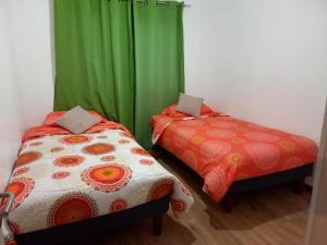 two beds in a room with green curtains at cabañas los treiles in Cumpeu +9 photos