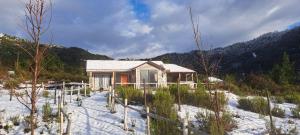 a small house in the snow in front of a mountain at cabañas los treiles in Cumpeu