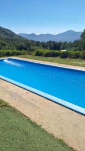 a large blue swimming pool with mountains in the background at cabañas los treiles in Cumpeu