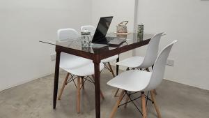a wooden table with white chairs and a laptop on it at Departamento Martinez San Isidro con AA y Wifi velocidad Ideal para quienes necesitan alojarse cerca de clínicas como Trinidad San Isidro Las Lomas o Fertilitis excelente acceso desde Panamericana y Thames espacio comodo tranquilo y totalmente equipado in Martínez