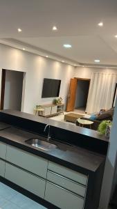 a kitchen with a sink and a living room at Casa de temporada Tarumã in Tangara da Serra