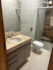 a bathroom with a sink and a toilet and a shower at Casa de temporada Tarumã in Tangara da Serra +9 photos
