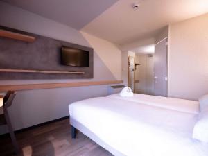 a bedroom with two beds and a tv on the wall at ibis budget Metz Sud in Augny