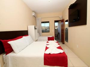 a bedroom with a bed with a red and white blanket at Hotel Caetité in Caetité