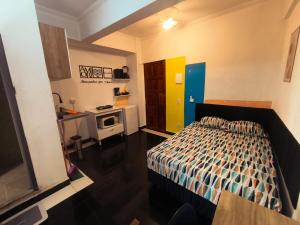 a small bedroom with a bed and a kitchen at Studio premium -- ap 06 in Diadema