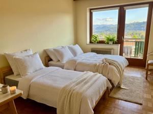 a bedroom with two beds and a window with a view at Apartment Karawankenblick with Lake View - Free Parking in Pörtschach am Wörthersee
