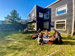 a group of people sitting on the grass in front of a house at Yagan house in Puerto Natales