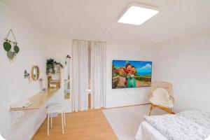 a white room with a bed and a desk and a painting on the wall at All in one Guesthouse in Incheon