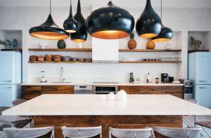 a kitchen with a white table and black pendant lights at 5BR Exclusive Beachfront Villa with Pool in Tulum in Balcheil