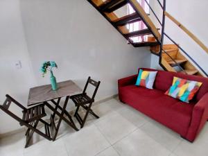 a living room with a red couch and a table at Conforto e Praticidade, Studio para 2 pessoas in Ponta Grossa