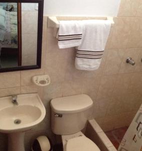 y baño con aseo, lavabo y toallas. en Hostal La Estancia, en Ica