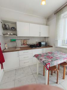 a kitchen with white cabinets and a table at Xata 1+2 in Almaty