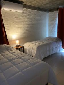a bedroom with two beds and a table with a lamp at Hotel La Morada in Treinta y Tres +4 photos