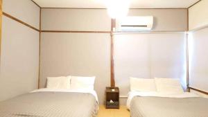 two beds in a room with white sheets at Hakone No Yado in Hakone