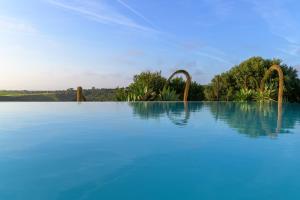 a swimming pool with blue water and trees in the background at Monte da Casa Telhada in Santiago do Cacém