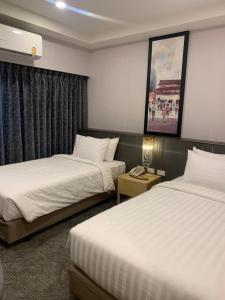 a hotel room with two beds and a table with a phone at โรงแรมสวนดุสิต เพลส in Ban Nong Chaeng