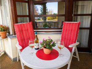 a table with two chairs and a bottle of wine and flowers at Ferienwohnung -West Häfele Blick in Hagnau +2 photos