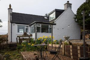 a house with a garden with chairs and flowers at Ard Dhub House Your 3 Bedroom cottage retreat in Waternish in Hallin