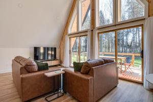 a living room with two couches and a tv at Secluded Architectural A-Frame w/ Soaring Windows & Fire Pit in South Haven