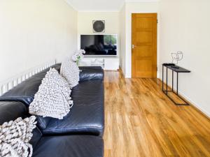 a black leather couch in a living room with a television at Luxury Seaview Escape - Mumbles in Oystermouth