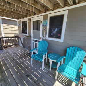 two blue chairs and a table on a porch at NC 12 56821-9 Condo in Hatteras
