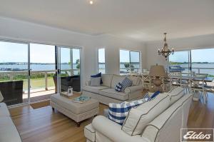 a living room with white furniture and a table with a view at Riverside Dream - 109 Barrage Rd in Goolwa South