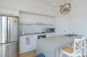 a kitchen with white cabinets and a stainless steel refrigerator at Riverside Dream - 109 Barrage Rd in Goolwa South
