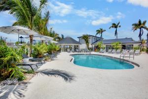 a resort pool with chairs and an umbrella at Tropic Isle At Anna Maria Island Inn in Bradenton Beach