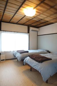 two beds in a room with a large window at 古民家宿そらいえ in Asago +39 photos