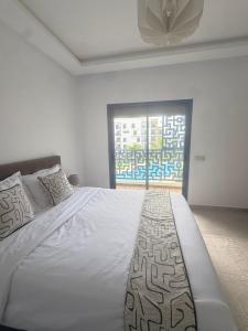 a white bedroom with a large bed and a window at Luxury Apartment in martil in Martil +13 photos