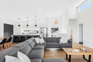 a living room with a gray couch and a kitchen at Lagoon Views in Hindmarsh Island