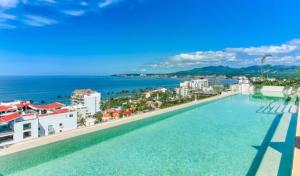 a pool on the roof of a building with a view of the ocean at Maralma Bucerias 1 half Blocks from Beach Sleeps 4 in Bucerías