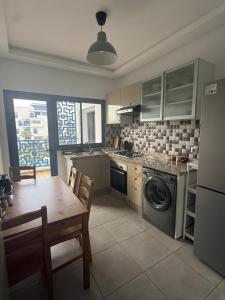 a kitchen with a table and a washing machine at Luxury Apartment in martil in Martil