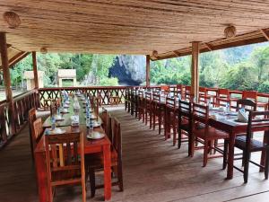 a long dining room with tables and chairs on a deck at Namnoncave Resort in Ban Namnon