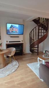 a living room with a flat screen tv and a staircase at Le cocoon de choupette in Cuvilly