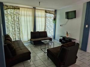 ein Wohnzimmer mit zwei Sofas und einem Fernseher in der Unterkunft Casa Nicolette in Uruapan del Progreso