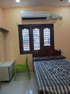 a bedroom with a bed and a green chair and window at Sri Durga Nilayam in Bhadrāchalam