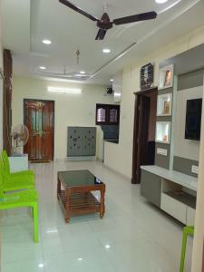 a living room with a table and a green chair at Sri Durga Nilayam in Bhadrāchalam