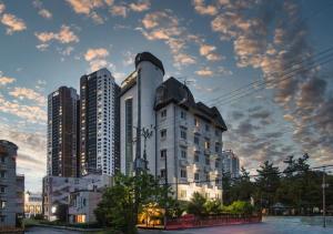 a tall white building in front of tall buildings at Hotel YAM Yeosu Hakdong in Yeosu