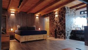 a bedroom with a bed and a stone wall at Mazamitla Pinos del Rio in Mazamitla