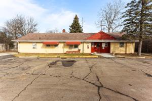 a yellow house with a red door on a street at Budget INN in Flint