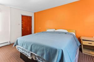 a bedroom with a bed with an orange wall at Budget INN in Flint