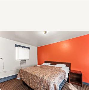 a bed in a room with an orange wall at Budget INN in Flint