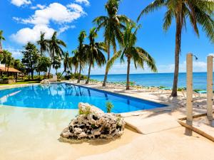 a swimming pool with palm trees and the ocean at Beachfront condo with loft and sea views in Puerto Aventuras