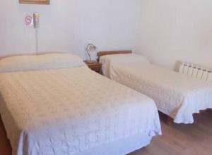 two beds in a room with white sheets at Salta Hotel in Venado Tuerto