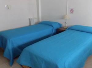 two beds in a room with blue sheets at Salta Hotel in Venado Tuerto