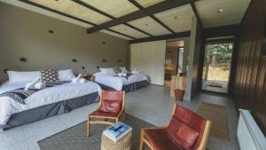 a bedroom with two beds and a chair at Hotel Patagonia House in Coihaique