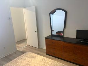 ein Schlafzimmer mit einer Kommode, auf der ein Spiegel steht in der Unterkunft EasyStay in Sherbrooke